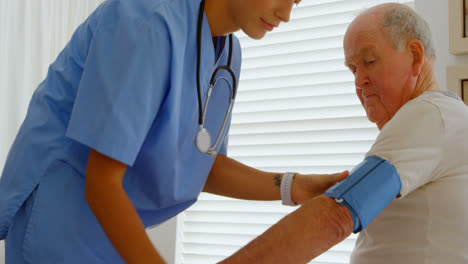 Side-view-of-young-Caucasian-female-doctor-measuring-blood-pressure-of-senior-man-at-home-4k