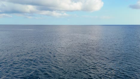 Mesmerizing-overview-of-Caribbean-ocean-water-surface-and-sky,-aerial-pullback-and-rise