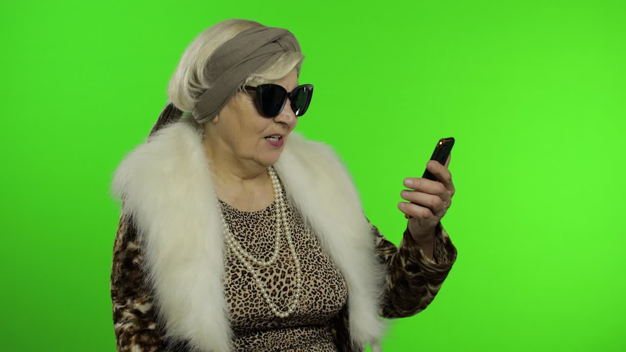 노인 백인 할머니가 스마트폰을 사용하여 비디오 통화를합니다.