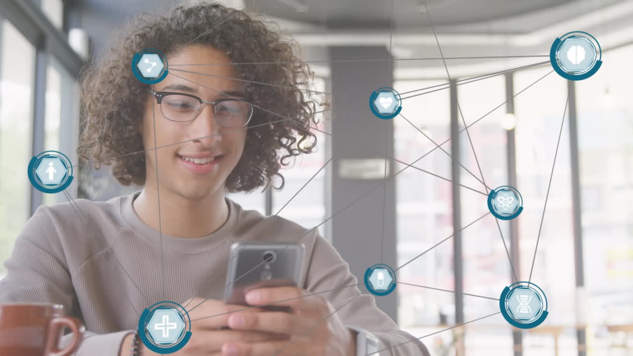 animación de una red de iconos digitales contra un hombre biracial sonriendo mientras usa un teléfono inteligente en una cafetería