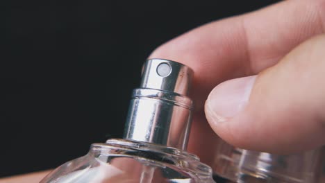 man takes off cap from perfume bottle on dark background