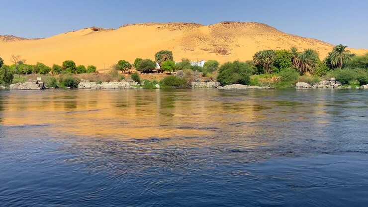 Little oasis landscape on the banks of the Nile with a huge dune with many green vegetation at its base