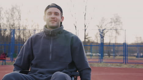 young disabled man in wheelchair looking at camera in basketball court