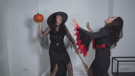two witches playing with a pumpkin