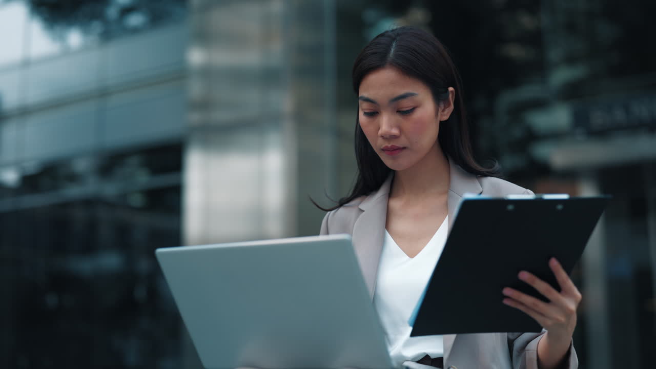 Businesswoman working outdoors with laptop and clipboard