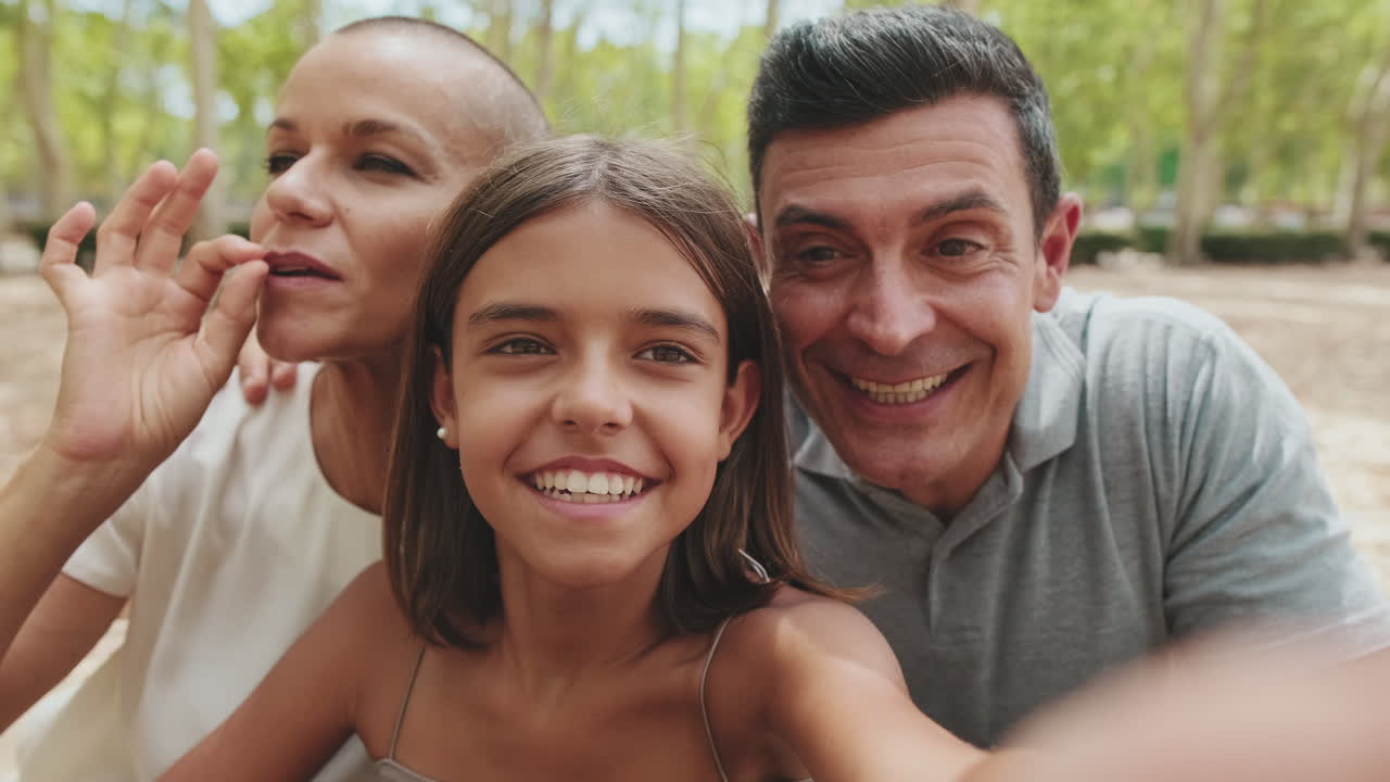 Glad familie tager en selfie og laver sjove ansigter i en park
