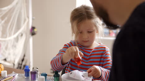 father and daughter making halloween masks at home together