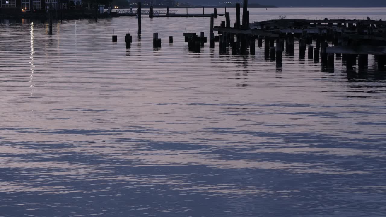 una mirada pacífica a un muelle en ruinas y reflejos sobre el agua mientras el sol se pone sobre el sur de puget sound