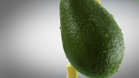 aguacate con rebanadas que caen sobre un fondo gris oscuro
