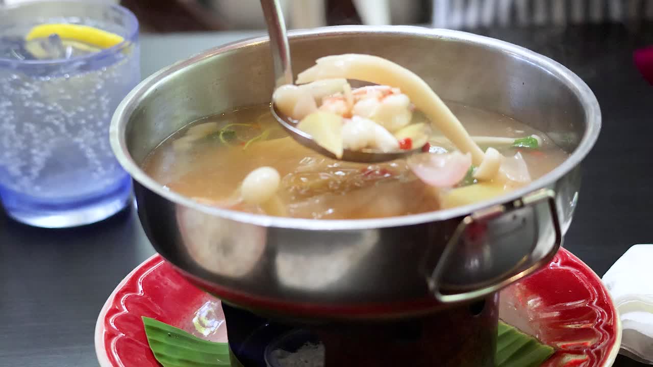 Cooking authentic Thai Isaan soup in hot pot at restaurant table