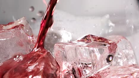 extreme close-up pouring red wine on ice cubes in slow motion shot