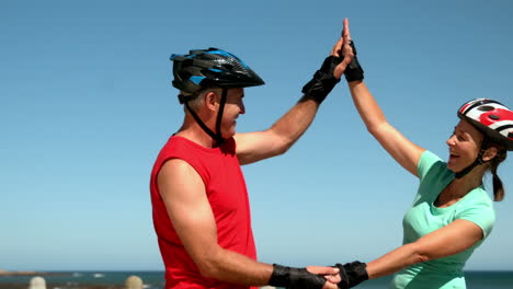 Älteres-Paar-Fährt-Inlineskaten-Am-Pier-Entlang-Und-Gibt-Sich-Ein-High-Five