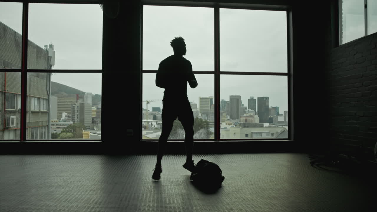 Silhouette of a Man in a Gym Overlooking the City