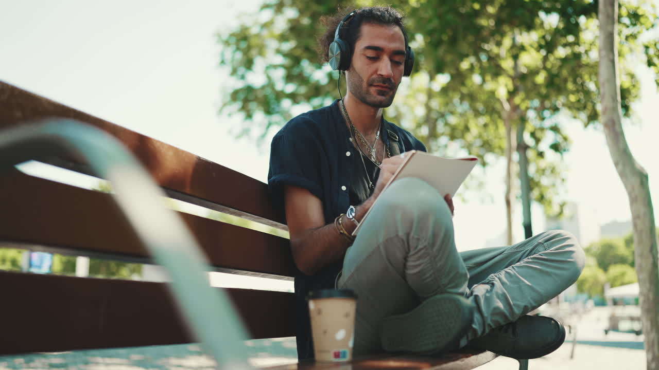 Homme avec un casque écrivant sur un banc à l’extérieur