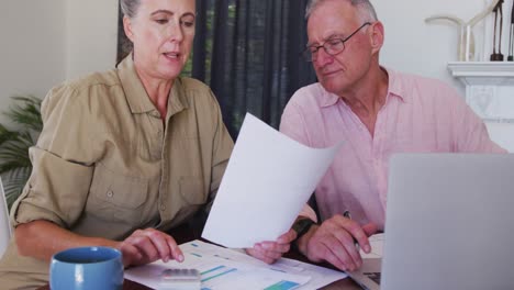 caucasian senior couple with laptop calculating finances together at home