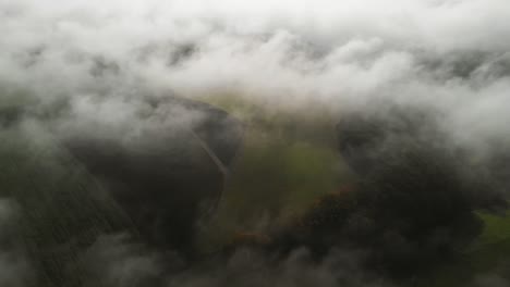 A-morning-with-fog-in-a-rural-area-of-Luxembour,-a-tilt-up-revealing-a-windturbine