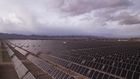 Aerial-Drone-Footage-of-Solar-Panel-Field-in-Joshua-Tree-National-Park-on-a-Sunny-Day-with-rainbow-in-the-background,-slow-horizontal-pan