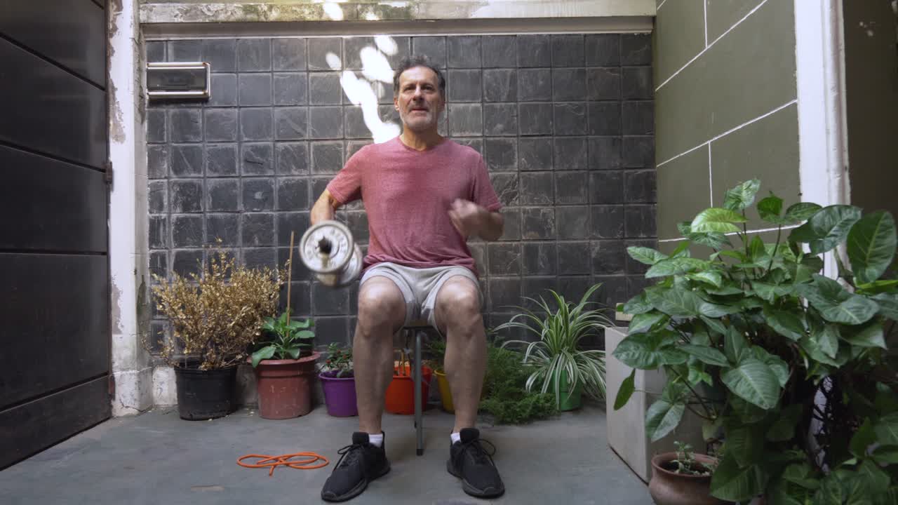 An older man holds a dumbbell and performs a controlled seated side bend, targeting his oblique muscles and core stability in an outdoor setting