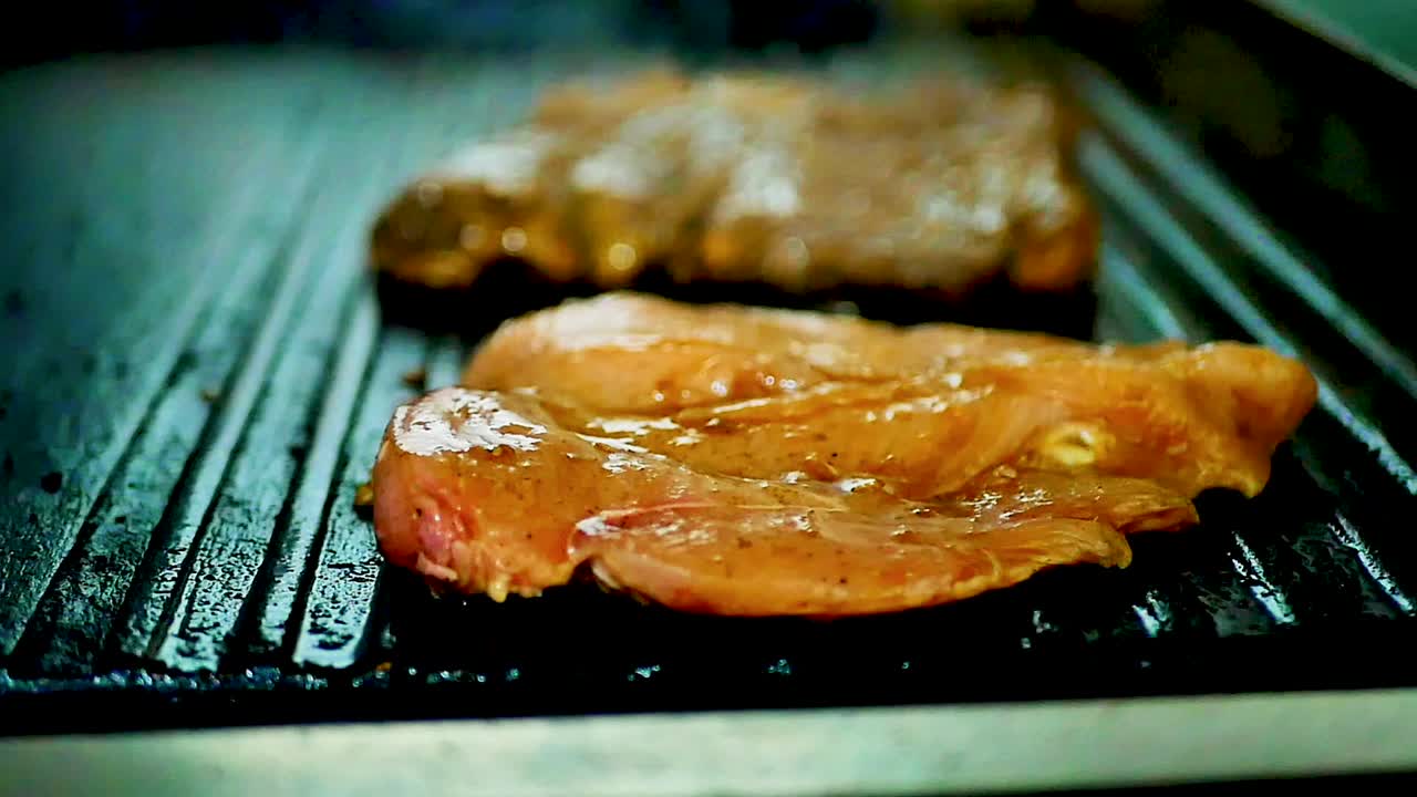 Raw marinade chicken sizzling on the grill with smoke, orbit shot