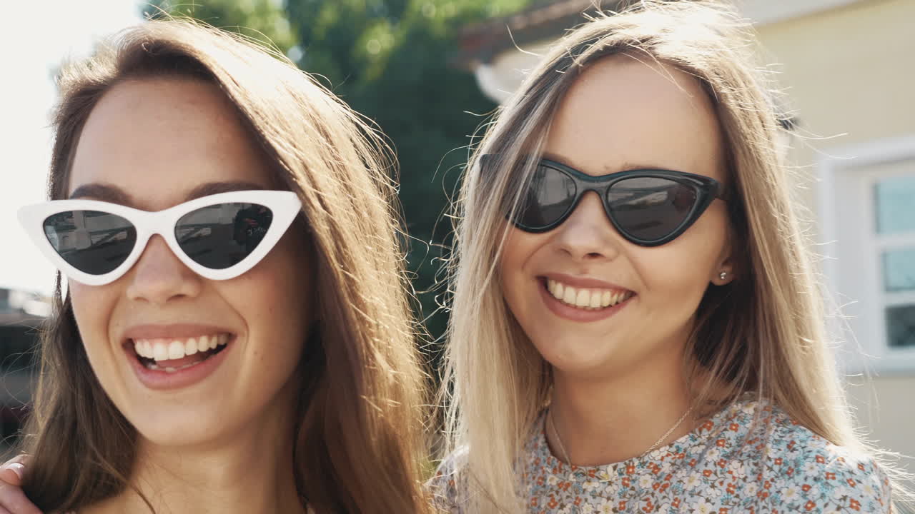 две подруги смеются на открытом воздухе.