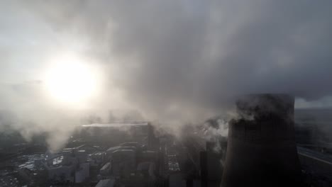 aerial pull back reveal of uk power station cooling towers through atmospheric steam emissions at sunrise