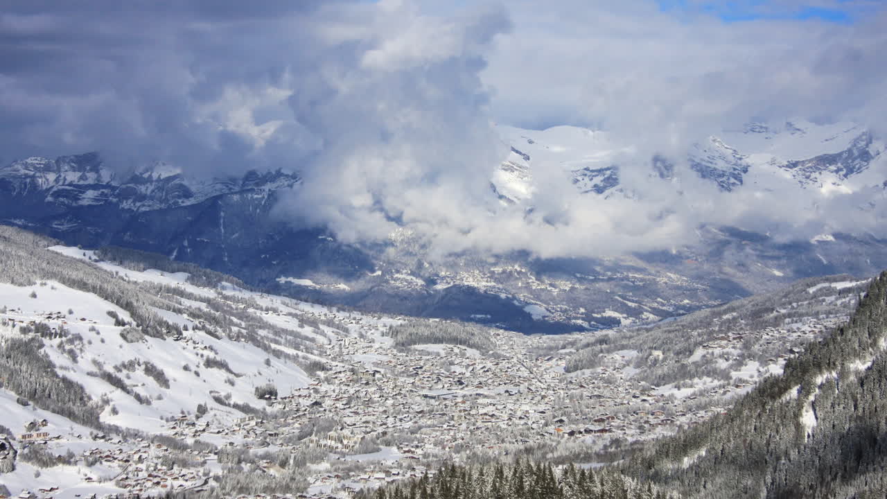 Time-lapse awan bergerak di atas pegunungan dan kota Megeve di Pegunungan Alpen Prancis saat musim dingin.