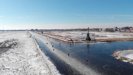 Patinaje-Sobre-Hielo-En-Los-Países-Bajos-Canales-Congelados-De-Invierno,-Vista-Aérea-Del-Molino-De-Viento