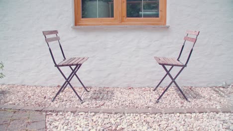 two empty wooden folding chairs on a gravel patio