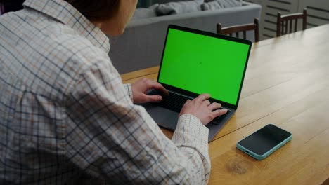 person working on a laptop with a green screen