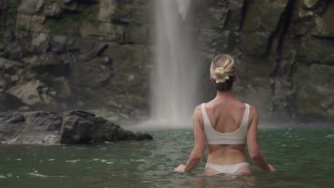 mujer europea en buen estado en bikini blanco de pie en la piscina de la cascada, eco chontales