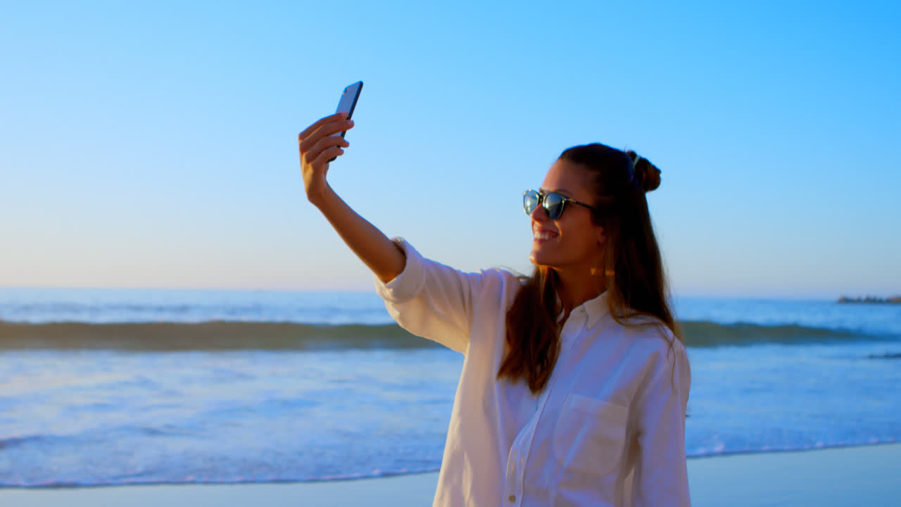 mujer tomando una selfie con teléfono móvil en la playa 4k