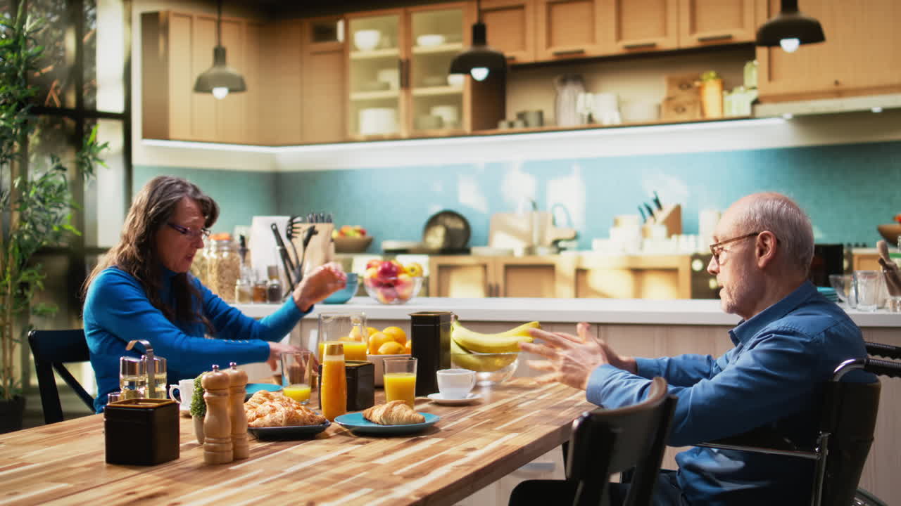 Elderly man wheelchair user drinking coffee at breakfast with his wife