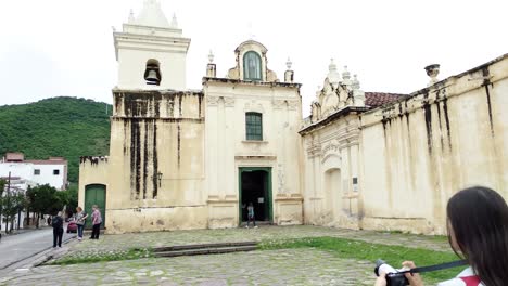 hembra en la parte superior blanca tomando una fotografía del convento san , salta exuberante cordillera verde en segundo plano.