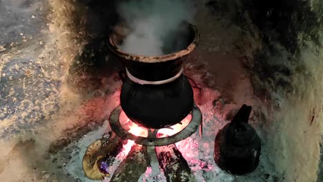 moroccan couscous cooking on a couscoussier steamer to steam it
on a wooden fire in a fireplace, smoke and flame surround the pot-3