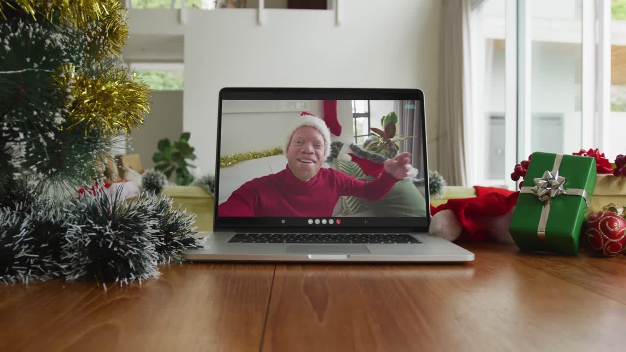 hombre afroamericano albino sonriente con sombrero de santa en una videollamada de navidad en una computadora portátil