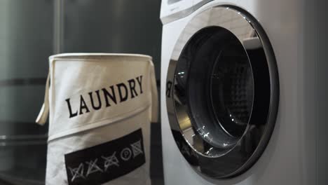 4k stationary shot of a man doing laundry and throwing white linen into a washing machine