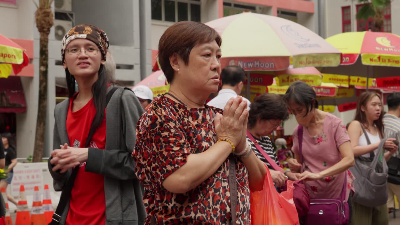 Woman in prayer outside Kwan Im Tong temple, Bugis, Singapore