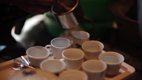 african woman adding sugar to different coffee cups, close up hand