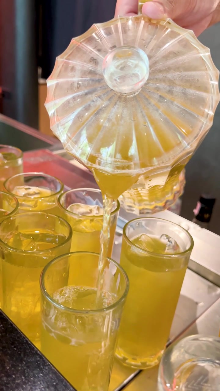 Barman che versa una bevanda gialla rinfrescante in bicchieri con ghiaccio.