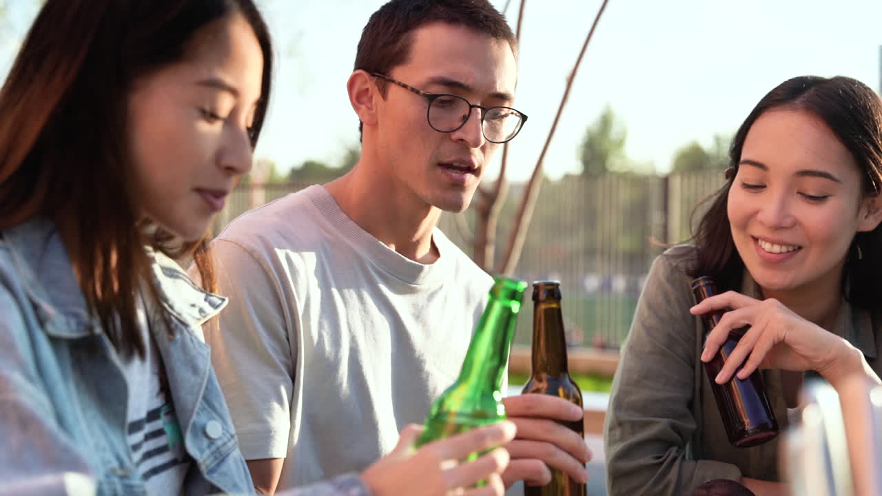 화창한 날 야외 테이블에 앉아 이야기하고 맥주를 마시는 세 명의 일본 친구 그룹 1