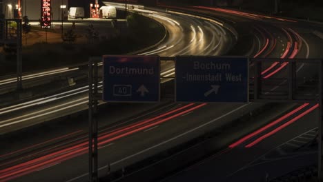 cars speed past bochum autobahn exit and fuel station, night timelapse
