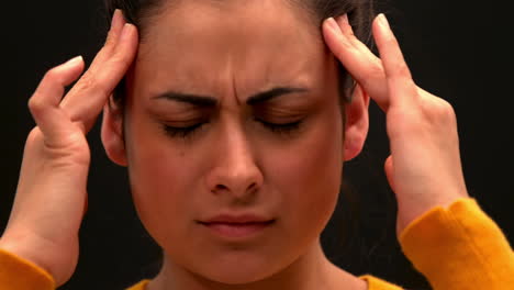 sick young woman rubbing her head on black background