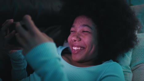 teenage girl browsing mobile phone in the living room at night and having fun