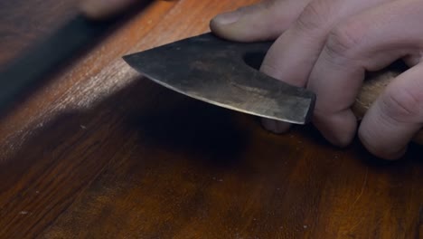 Cut-edge-on-small-Viking-hatchet-axe-is-sharpened-using-a-whetstone