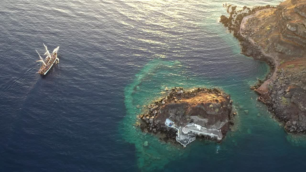 video de vista aérea de un hermoso velero navegando en el mar egeo azul profundo durante la puesta de sol, santorini, grecia