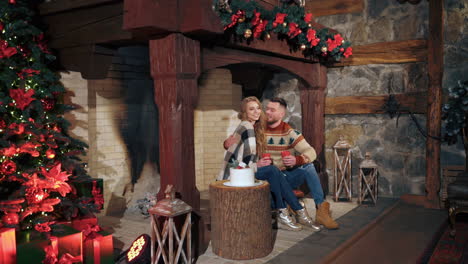 christmas decorated fireplace in a house before holidays. young couple warms near fireplace. man and woman in love.