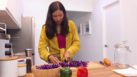mujer cortando repollo rojo en la cocina