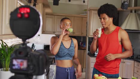 Two-diverse-male-and-female-friends-making-culinary-video-blog-in-kitchen