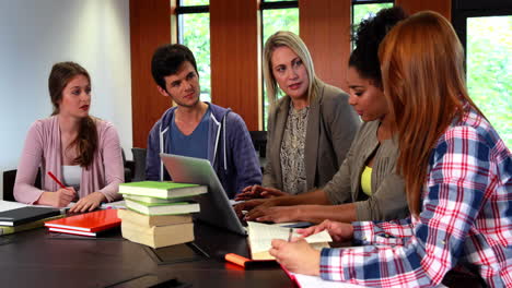 estudiantes y tutor discutiendo en la biblioteca