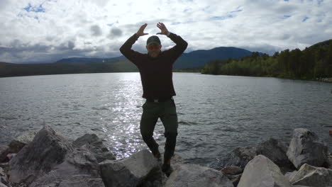 male hiker standing on rocks in front of a lake in saltoluokta, northern sweden